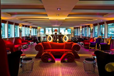 Bateau amarré le long d'un quai, avec une table dressée et des verres à vin sur le pont arrière.