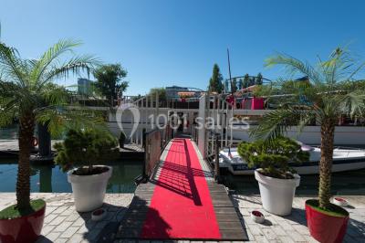 Bateau amarré le long d'un quai, avec une table dressée et des verres à vin sur le pont arrière.