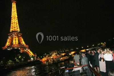 Bateau amarré le long d'un quai, avec une table dressée et des verres à vin sur le pont arrière.