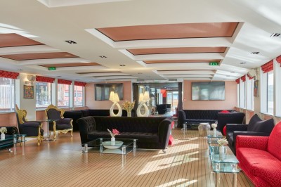 Bateau amarré le long d'un quai, avec une table dressée et des verres à vin sur le pont arrière.