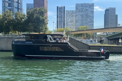 Bateau amarré le long d'un quai, avec une table dressée et des verres à vin sur le pont arrière.