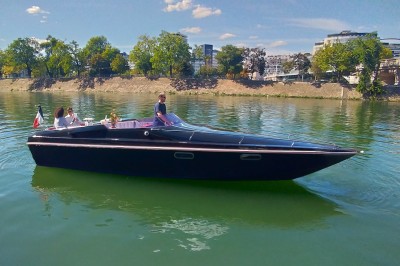 Bateau amarré le long d'un quai, avec une table dressée et des verres à vin sur le pont arrière.