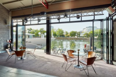 Miniature L'Atelier du France Bateau amarré le long d'un quai, avec une table dressée et des verres à vin sur le pont arrière.