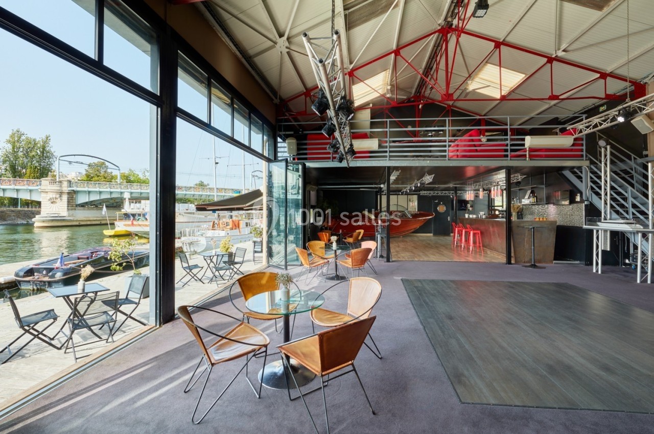 L'Atelier du France Salle lumineuse avec verrière, mobilier moderne, vue sur un quai et un pont, ambiance industrielle et conviviale.
