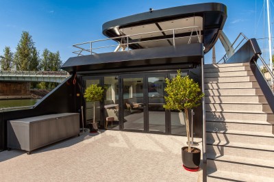 Miniature La Perle Noire Bateau amarré le long d'un quai, avec une table dressée et des verres à vin sur le pont arrière.