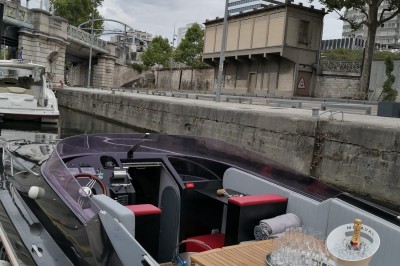 Miniature Le Black Swan Bateau amarré le long d'un quai, avec une table dressée et des verres à vin sur le pont arrière.