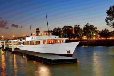 Miniature Le Clipper Paris Bateau amarré le long d'un quai, avec une table dressée et des verres à vin sur le pont arrière.