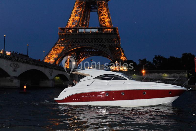 Le James Un yacht blanc et rouge navigue sur la Seine, avec la tour Eiffel illuminée en arrière-plan.