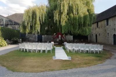 Salle de réception décorée avec des tables rondes dressées, des chaises blanches et un plafond orné de guirlandes suspendues.