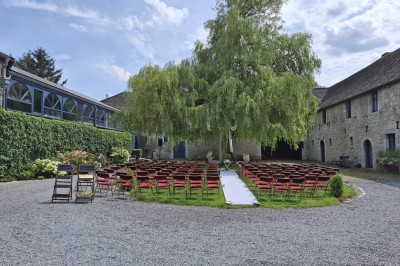 Salle décorée pour un repas festif avec longues tables dressées, guirlandes lumineuses et grand sapin illuminé.