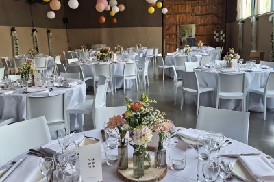 Salle décorée pour un repas festif avec longues tables dressées, guirlandes lumineuses et grand sapin illuminé.