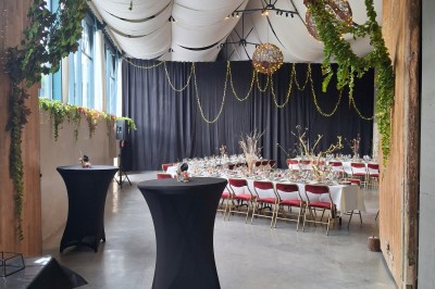 Salle décorée pour un repas festif avec longues tables dressées, guirlandes lumineuses et grand sapin illuminé.