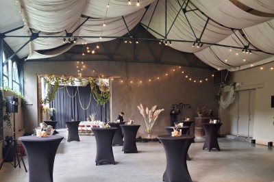 Salle décorée pour un repas festif avec longues tables dressées, guirlandes lumineuses et grand sapin illuminé.
