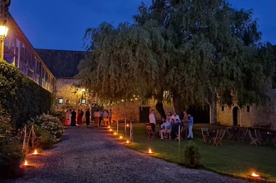 Salle décorée pour un repas festif avec longues tables dressées, guirlandes lumineuses et grand sapin illuminé.