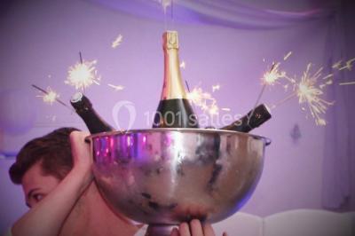 Mur en pierre ocre avec jardinières en bois garnies de fleurs colorées, entouré de végétation et éclairé par la lumière du…