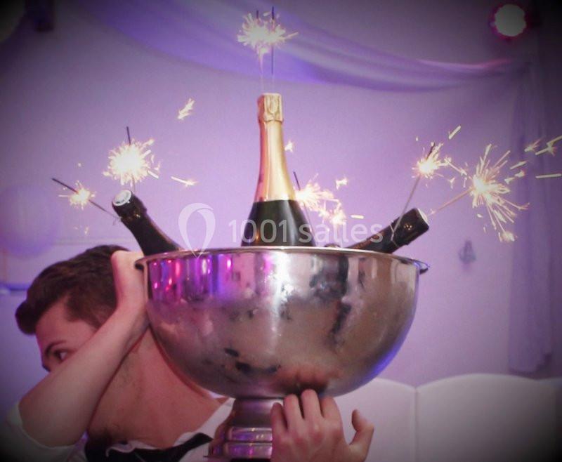 Un grand seau en métal contenant des bouteilles de champagne ornées de cierges magiques allumés.