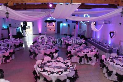 Mur en pierre ocre avec jardinières en bois garnies de fleurs colorées, entouré de végétation et éclairé par la lumière du…
