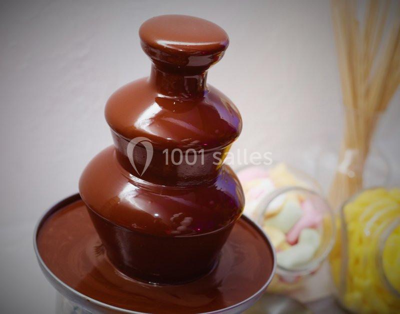 Fontaine à chocolat en fonctionnement avec des bonbons colorés et des guimauves en arrière-plan.