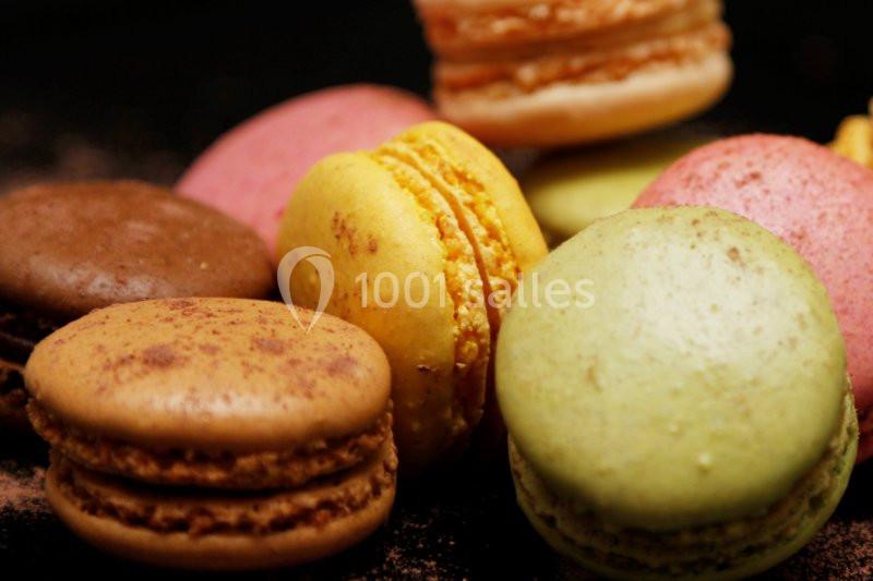 Assortiment de macarons colorés disposés sur une surface sombre.
