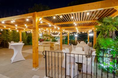 Mur en pierre ocre avec jardinières en bois garnies de fleurs colorées, entouré de végétation et éclairé par la lumière du…
