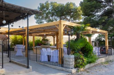Mur en pierre ocre avec jardinières en bois garnies de fleurs colorées, entouré de végétation et éclairé par la lumière du…