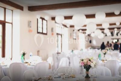 Bâtisse en pierre avec toit en tuiles, entourée de verdure, chemin en gravier et un chien sur la pelouse.