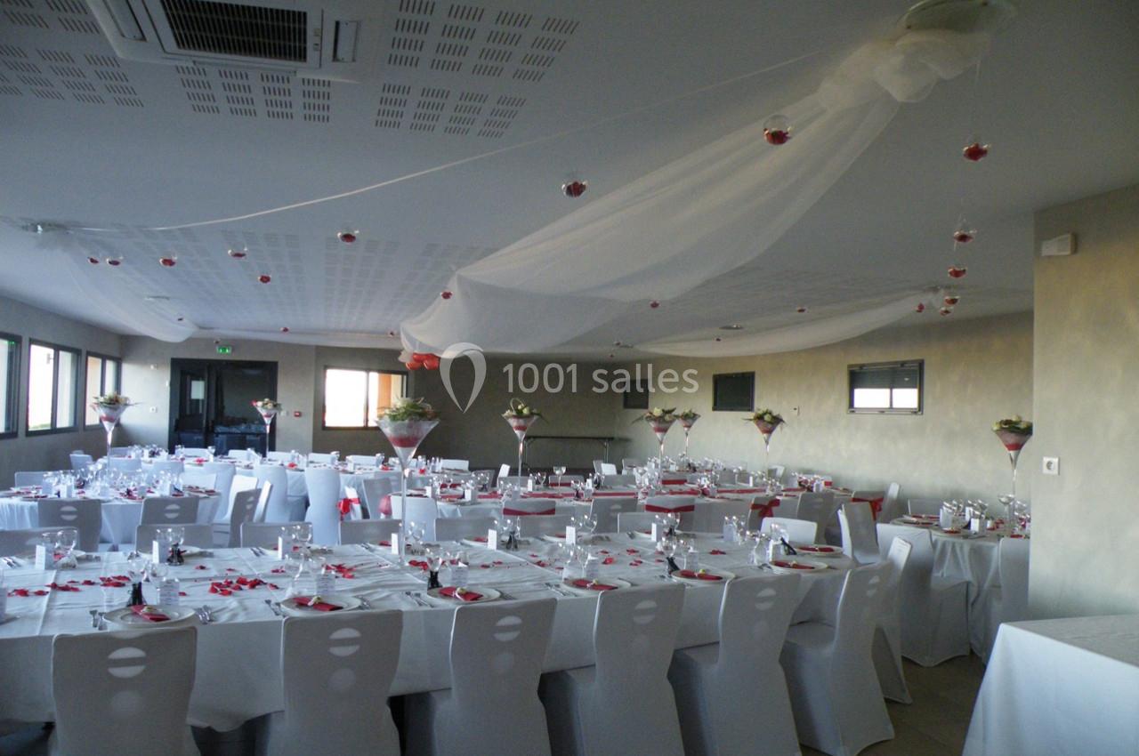 Salle de réception décorée avec des tables dressées, nappes blanches et centres de table fleuris.