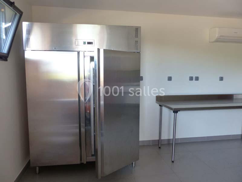 Réfrigérateur professionnel en inox ouvert dans une pièce lumineuse avec un plan de travail en métal.