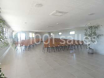 Bâtiment à un étage avec toit en tuiles, entouré de chemins, de pelouse et de vignes en arrière-plan.