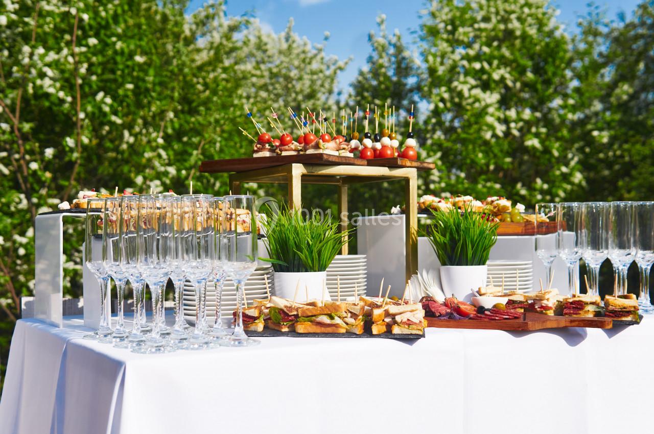 Table dressée en extérieur avec des amuse-bouches, des verres à pied et des décorations végétales.