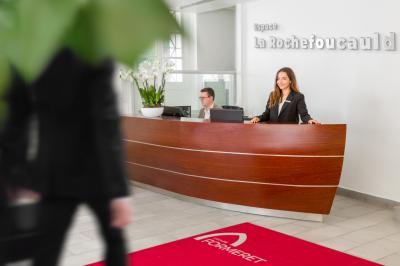 Salle de réunion lumineuse avec tables en U, chaises rouges, micros, écran mural et une plante verte.