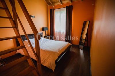 Miniature Location salle Alix (Rhône) - Domaine du Clos des Liesses #22 Chambre avec lit double, parquet clair, échelle en bois menant à une mezzanine, fenêtre avec rideaux et miroir debout.