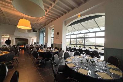 Grande maison à colombages éclairée en vert la nuit, avec des fenêtres illuminées et un porche couvert.