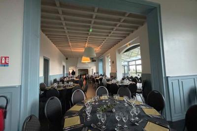 Grande maison à colombages éclairée en vert la nuit, avec des fenêtres illuminées et un porche couvert.