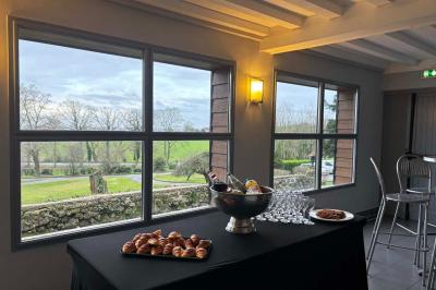 Grande maison à colombages éclairée en vert la nuit, avec des fenêtres illuminées et un porche couvert.