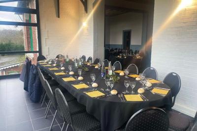 Grande maison à colombages éclairée en vert la nuit, avec des fenêtres illuminées et un porche couvert.