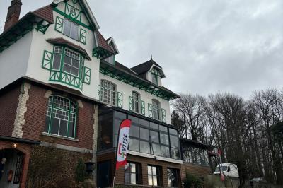 Grande maison à colombages éclairée en vert la nuit, avec des fenêtres illuminées et un porche couvert.