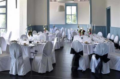 Grande maison à colombages éclairée en vert la nuit, avec des fenêtres illuminées et un porche couvert.