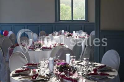 Grande maison à colombages éclairée en vert la nuit, avec des fenêtres illuminées et un porche couvert.