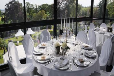 Grande maison à colombages éclairée en vert la nuit, avec des fenêtres illuminées et un porche couvert.