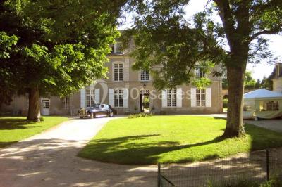 Salle à manger rustique avec murs en pierre, table en bois, chaises assorties et porte-fenêtre donnant sur l'extérieur.