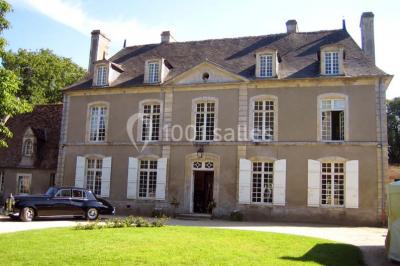 Salle à manger rustique avec murs en pierre, table en bois, chaises assorties et porte-fenêtre donnant sur l'extérieur.