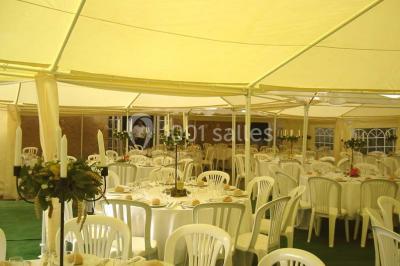Salle à manger rustique avec murs en pierre, table en bois, chaises assorties et porte-fenêtre donnant sur l'extérieur.