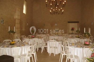 Salle à manger rustique avec murs en pierre, table en bois, chaises assorties et porte-fenêtre donnant sur l'extérieur.