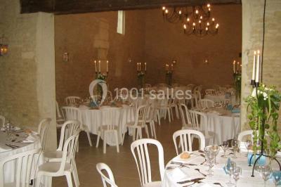 Salle à manger rustique avec murs en pierre, table en bois, chaises assorties et porte-fenêtre donnant sur l'extérieur.