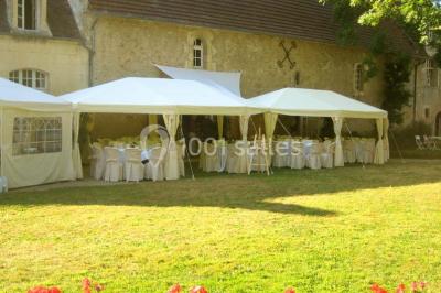 Salle à manger rustique avec murs en pierre, table en bois, chaises assorties et porte-fenêtre donnant sur l'extérieur.
