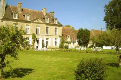 Salle à manger rustique avec murs en pierre, table en bois, chaises assorties et porte-fenêtre donnant sur l'extérieur.