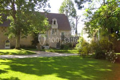 Salle à manger rustique avec murs en pierre, table en bois, chaises assorties et porte-fenêtre donnant sur l'extérieur.