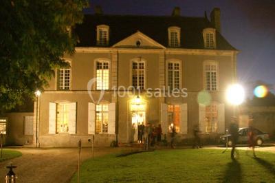 Salle à manger rustique avec murs en pierre, table en bois, chaises assorties et porte-fenêtre donnant sur l'extérieur.