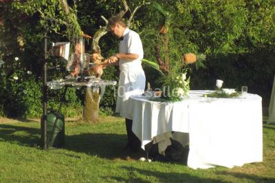 Salle à manger rustique avec murs en pierre, table en bois, chaises assorties et porte-fenêtre donnant sur l'extérieur.